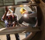 Two multi-ethnic workers in a metal fabrication factory inspecting a product, examining it with a flashlight. The mature man on the right is in his 40s and his African-American coworker is in his 30s.
