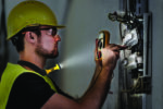 Electrician repairing circuit breakers in industrial electric panel.